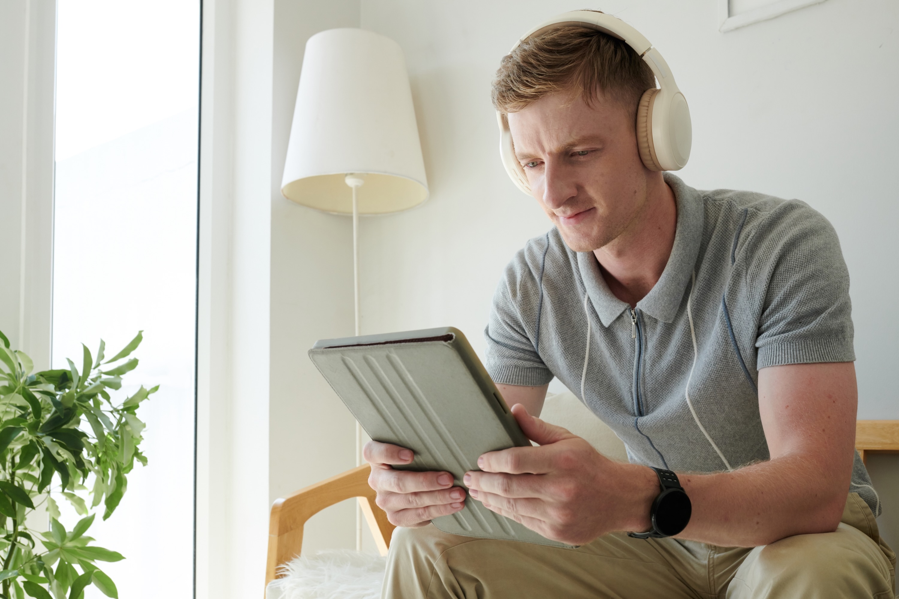 Man watching podcast with headphones on tablet