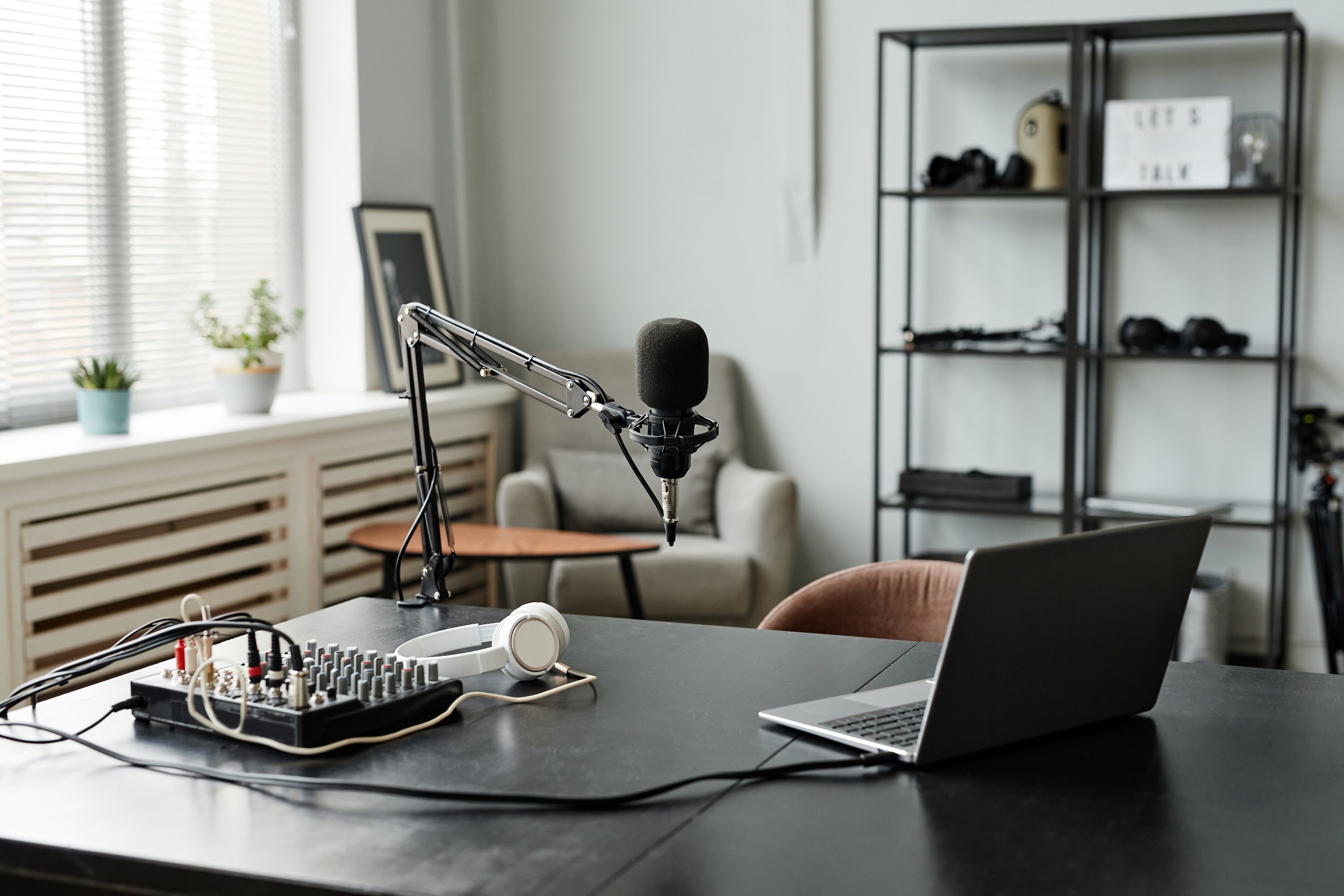 Microphone on stand and laptop on desk for home podcast recording session