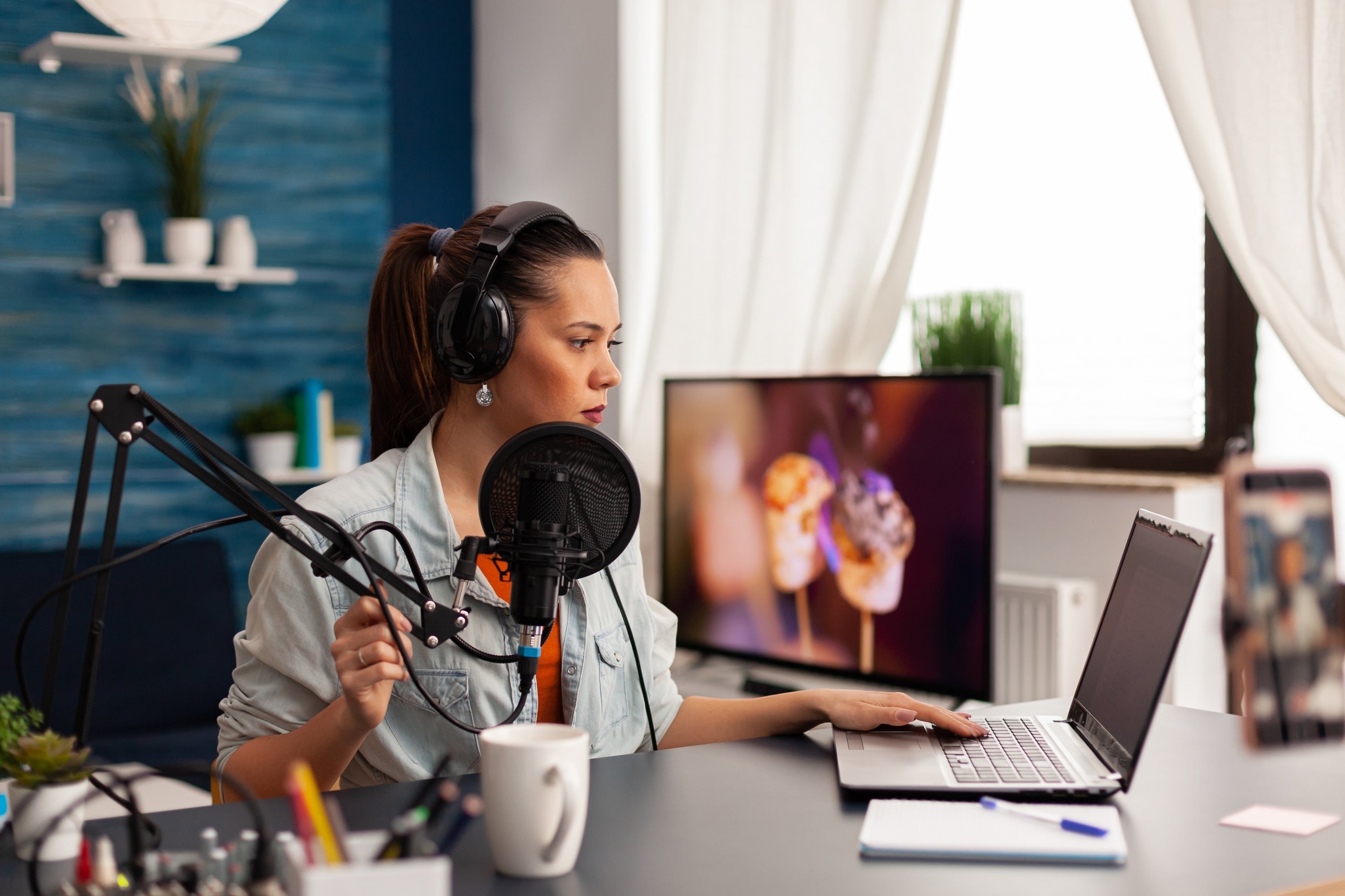 Woman recording podcast with mic and laptop