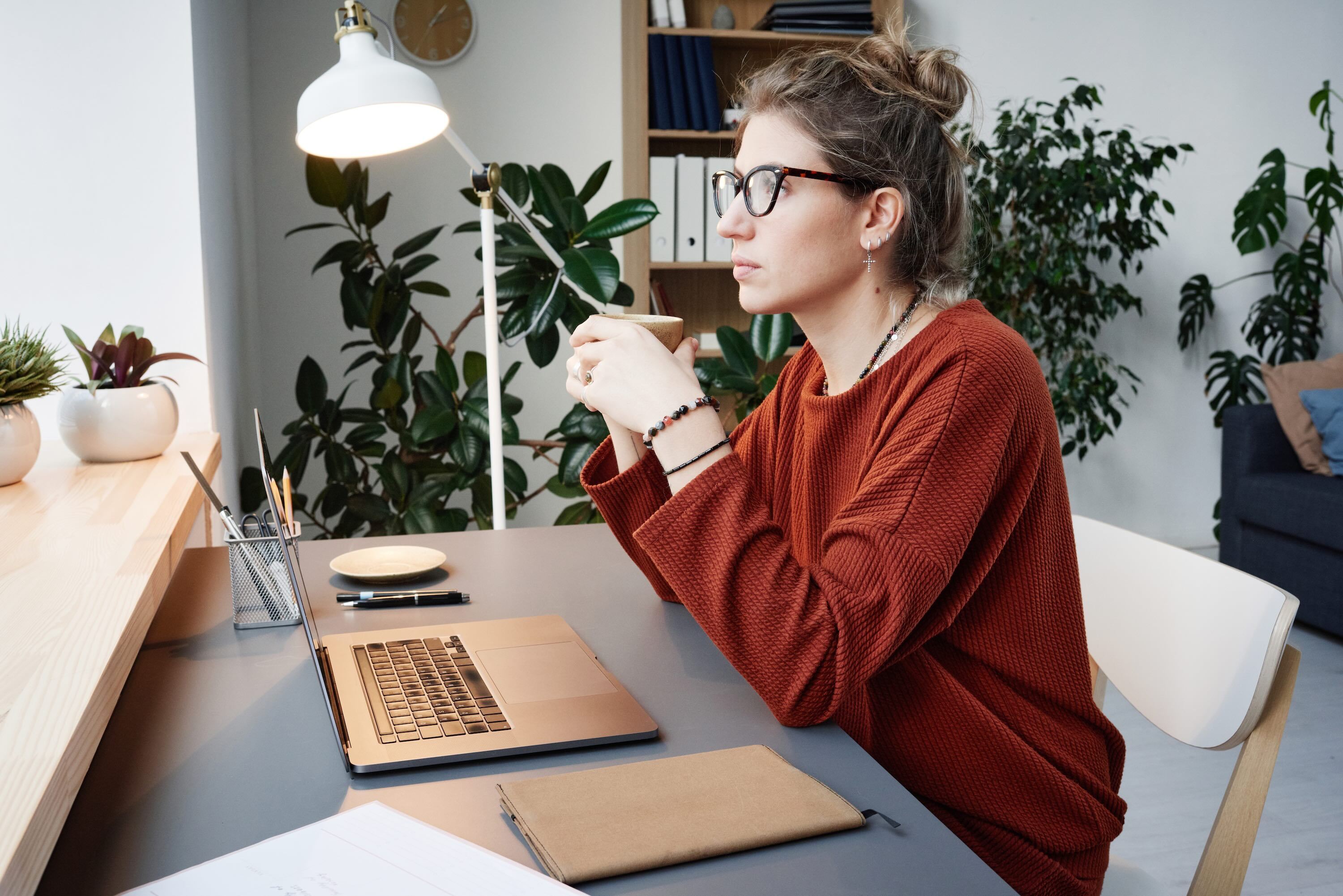 Woman working from home office in a her desk with laptop open