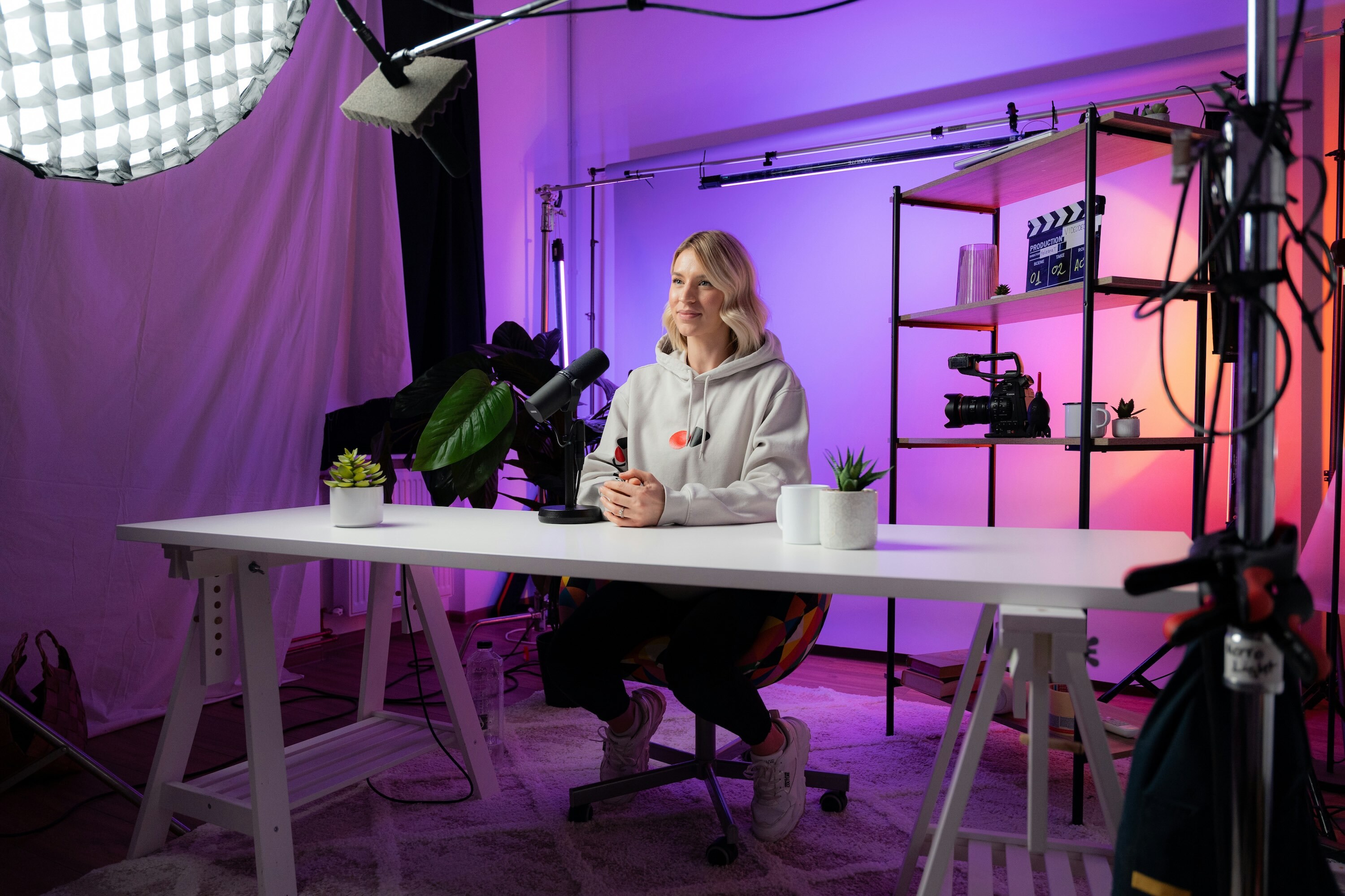 Woman sitting in a studio set with purple lighting recording a video podcast